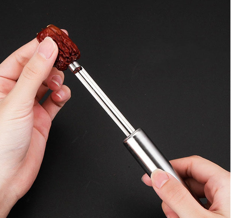 Person using a metal tool to open a dried fruit against a black background