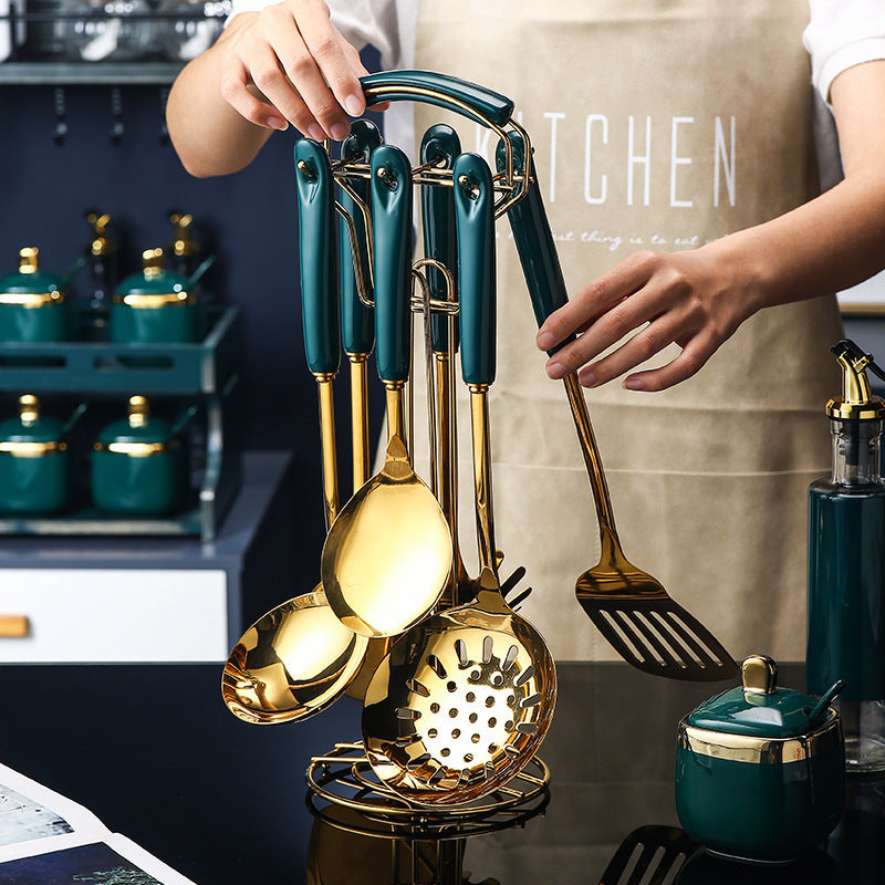 Set of gold and teal kitchen utensils held by a person wearing an apron.