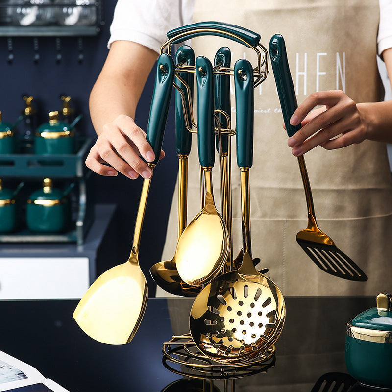 Set of gold and green kitchen utensils held by a person in a kitchen setting.