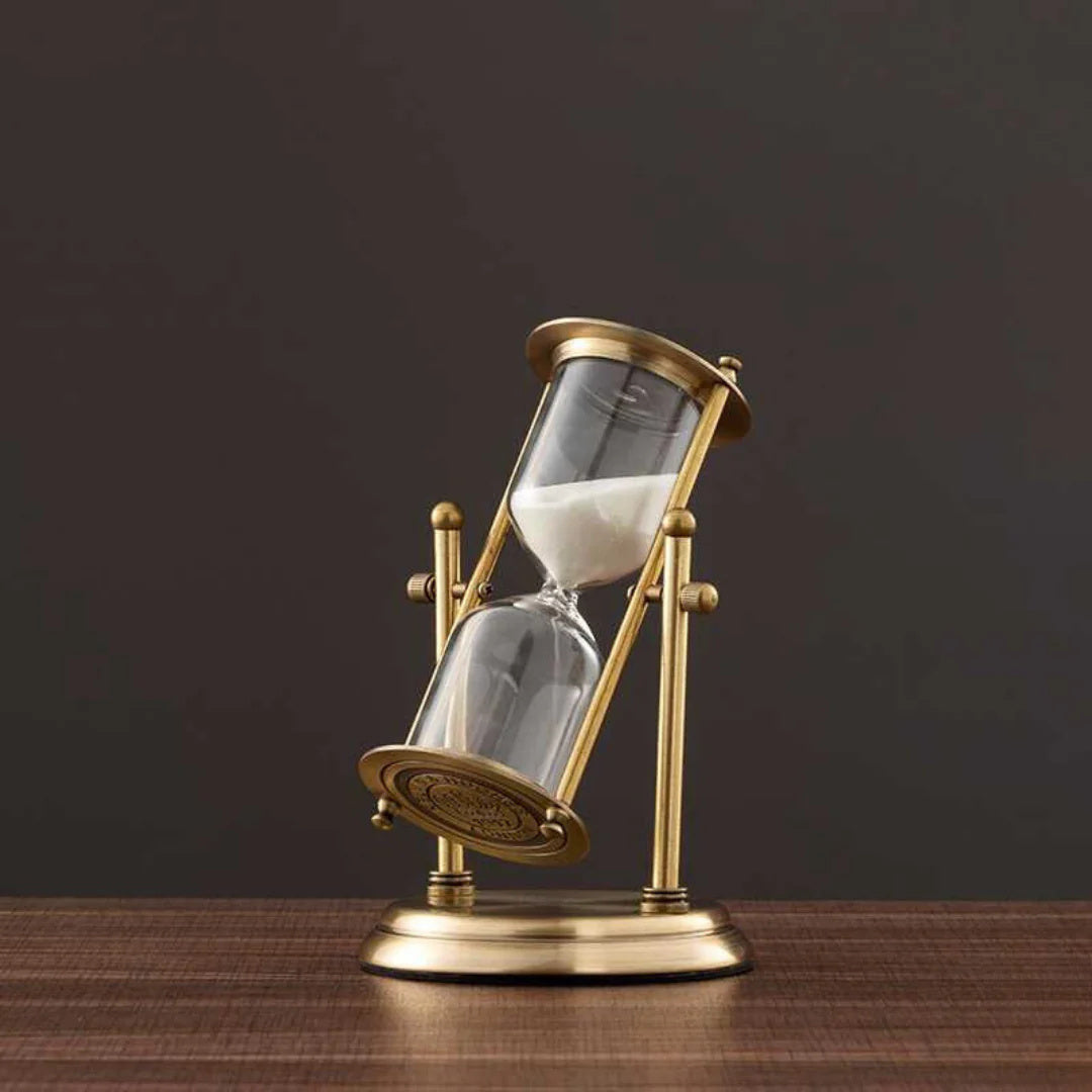 Vintage-style hourglass with brass casing on a wooden surface