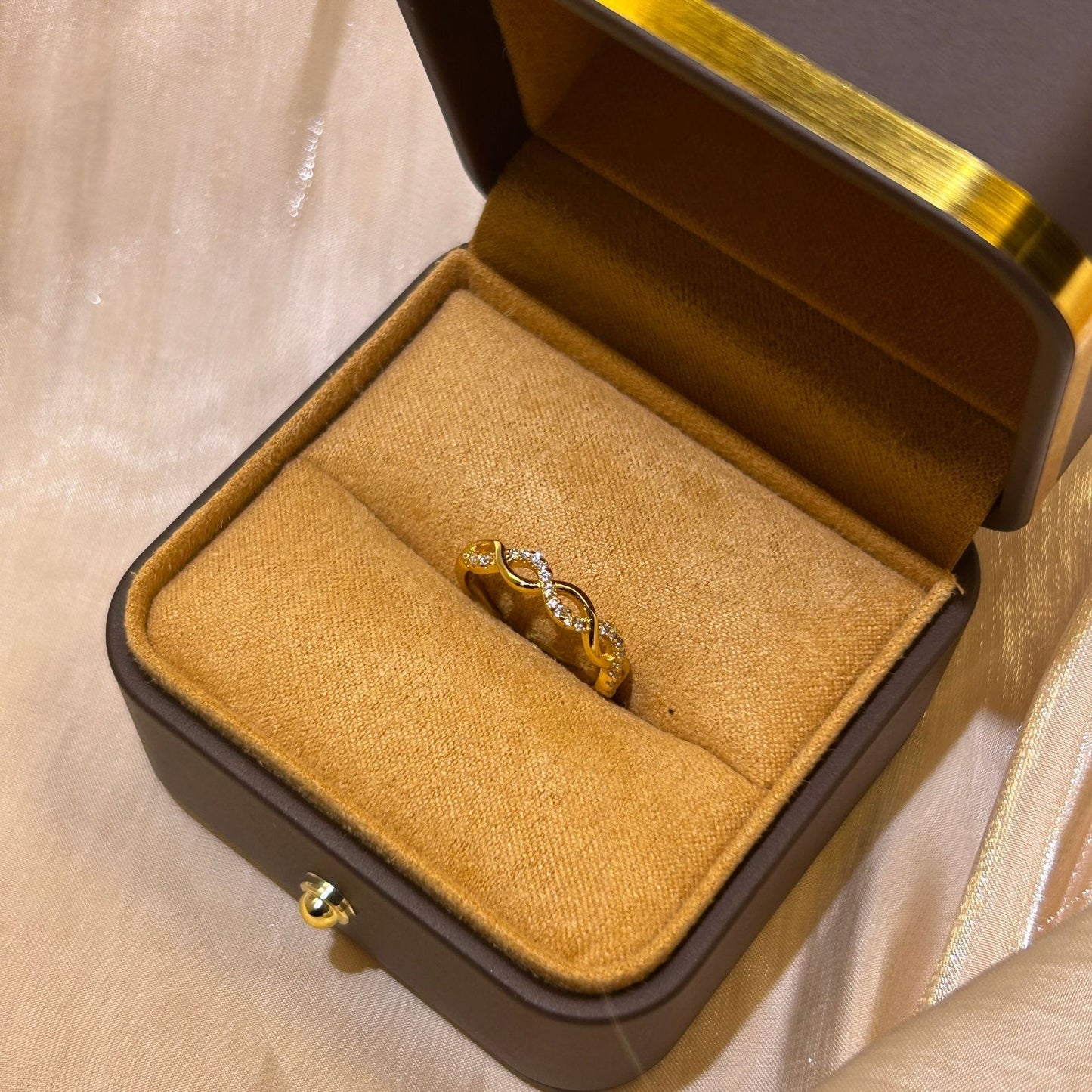 Gold ring with diamonds in a jewelry box on a beige fabric background
