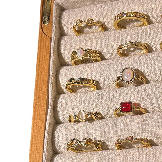 Collection of gold rings with various designs and gemstones in a jewelry box.