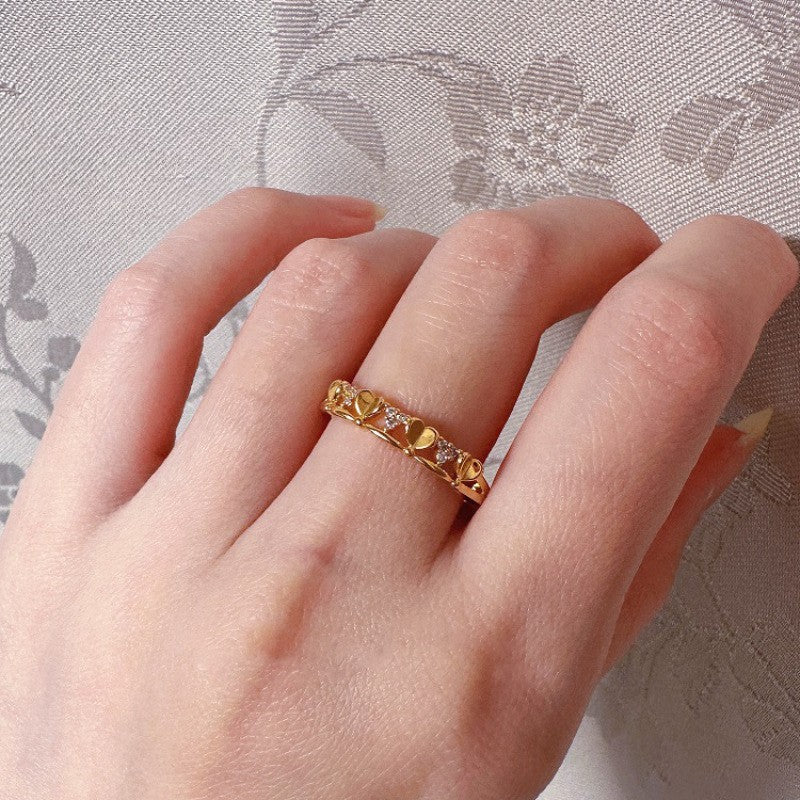 Gold ring with yellow gemstones on a hand against a floral-patterned background