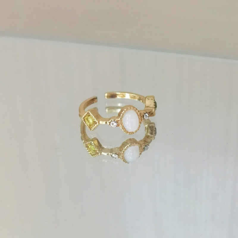 Gold ring with gemstones on a light gray background