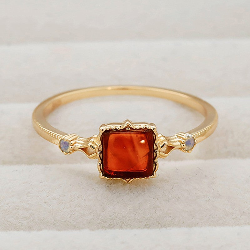 Gold ring with a red gemstone on a white background