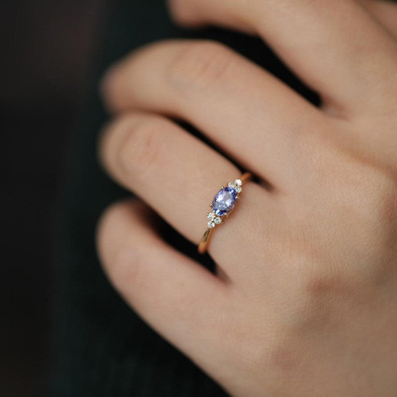 Close-up of a hand wearing a ring with a blue gemstone on a dark background