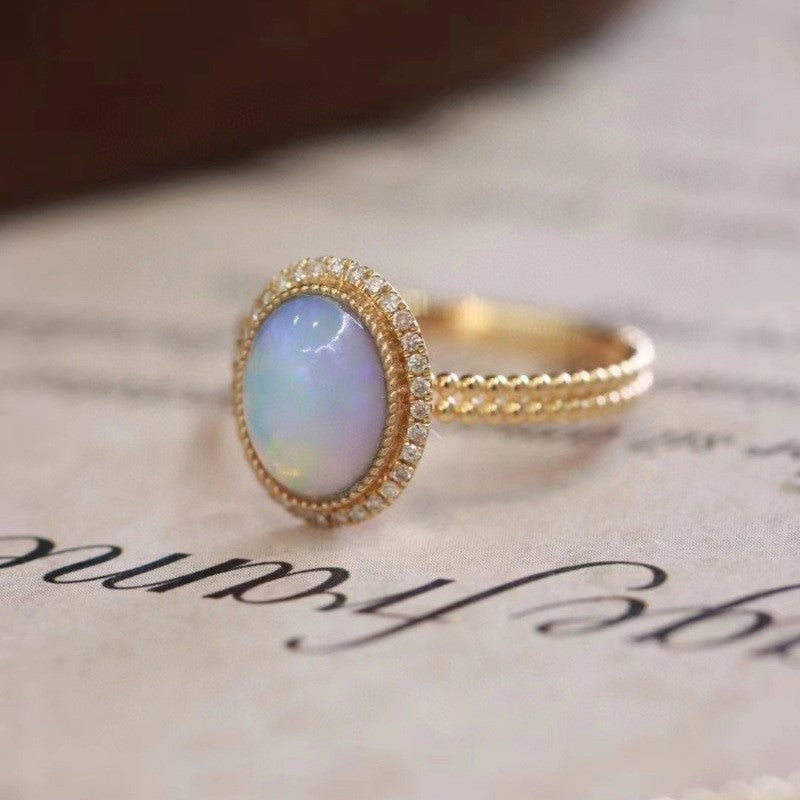 Gold ring with an opal stone on a textured surface