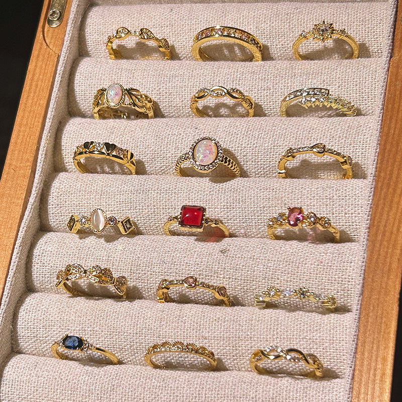 Collection of gold rings with various designs and gemstones displayed in a jewelry box.