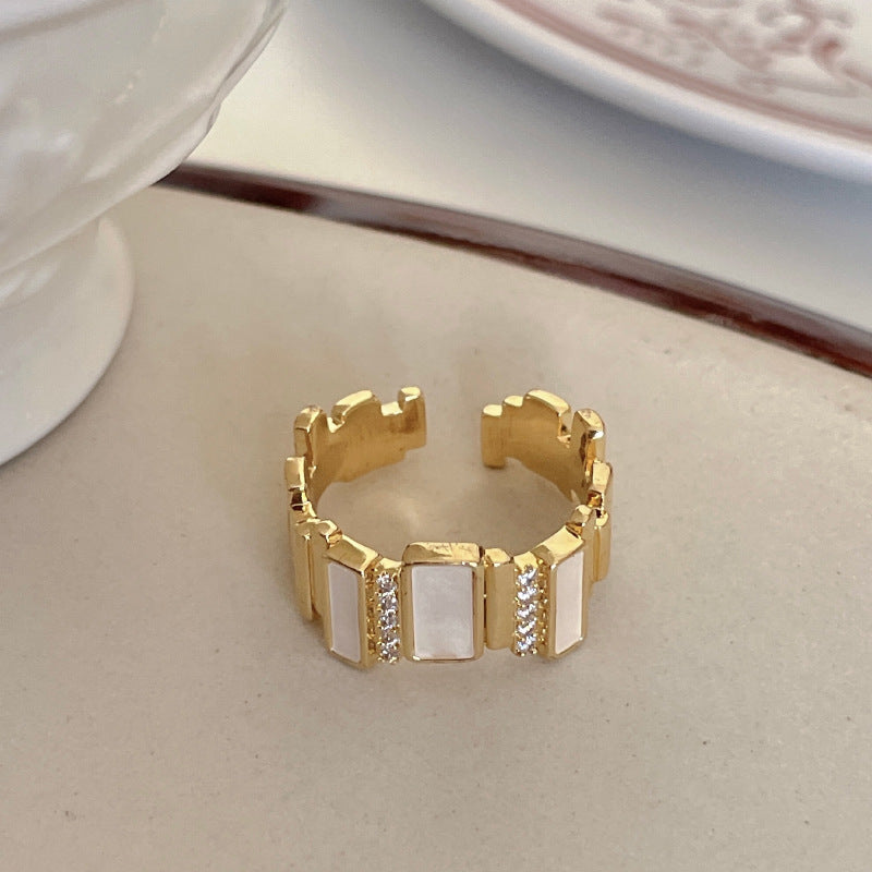 Gold ring with geometric design on a beige surface