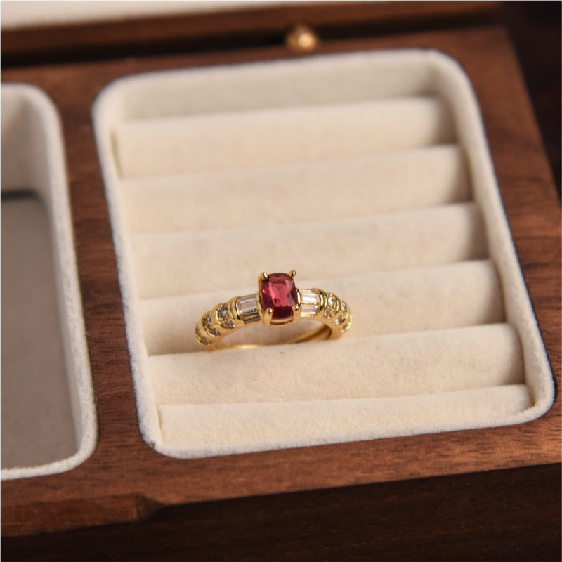 Gold ring with a red gemstone in a wooden jewelry box