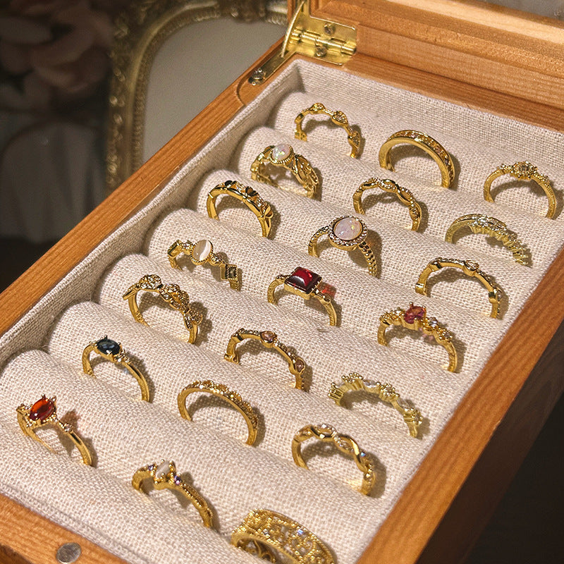 Collection of gold rings with gemstones in a wooden jewelry box.