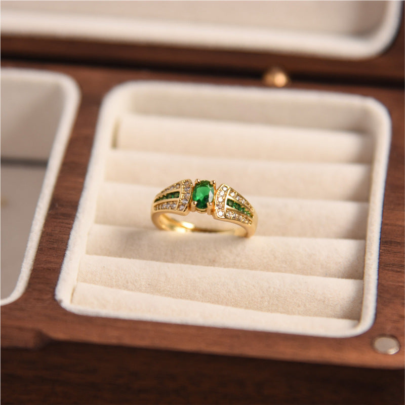 Gold ring with green gemstones in a jewelry box