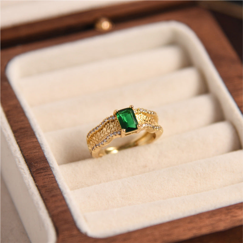 Gold ring with a green gemstone in a wooden box