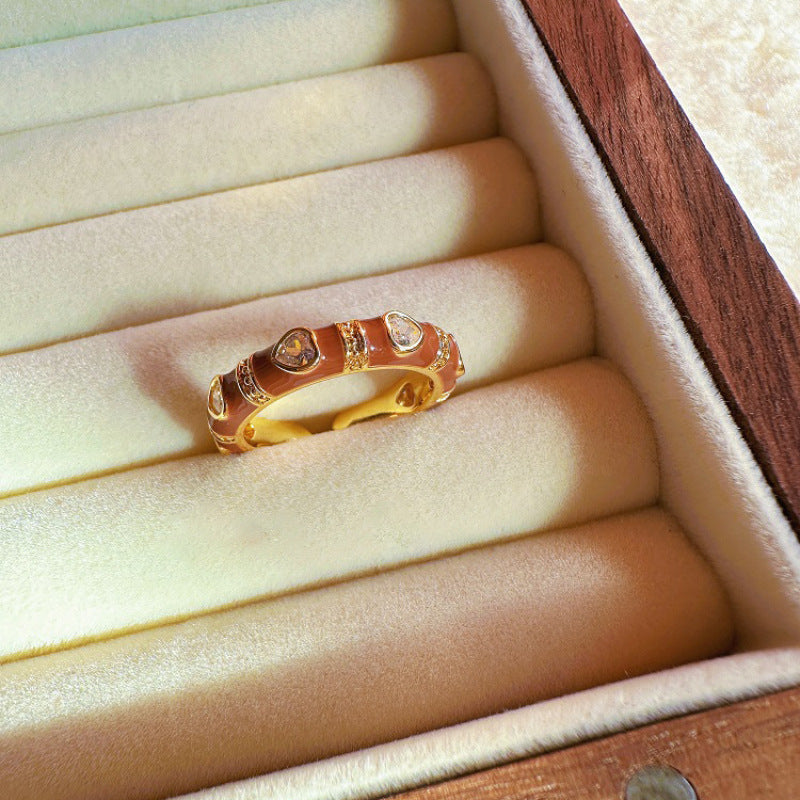 Gold ring with heart designs on a soft, beige cushion in a wooden box.