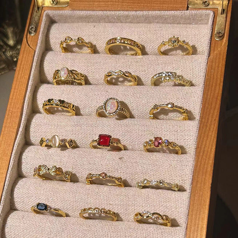 Collection of gold rings with gemstones displayed in a wooden box.