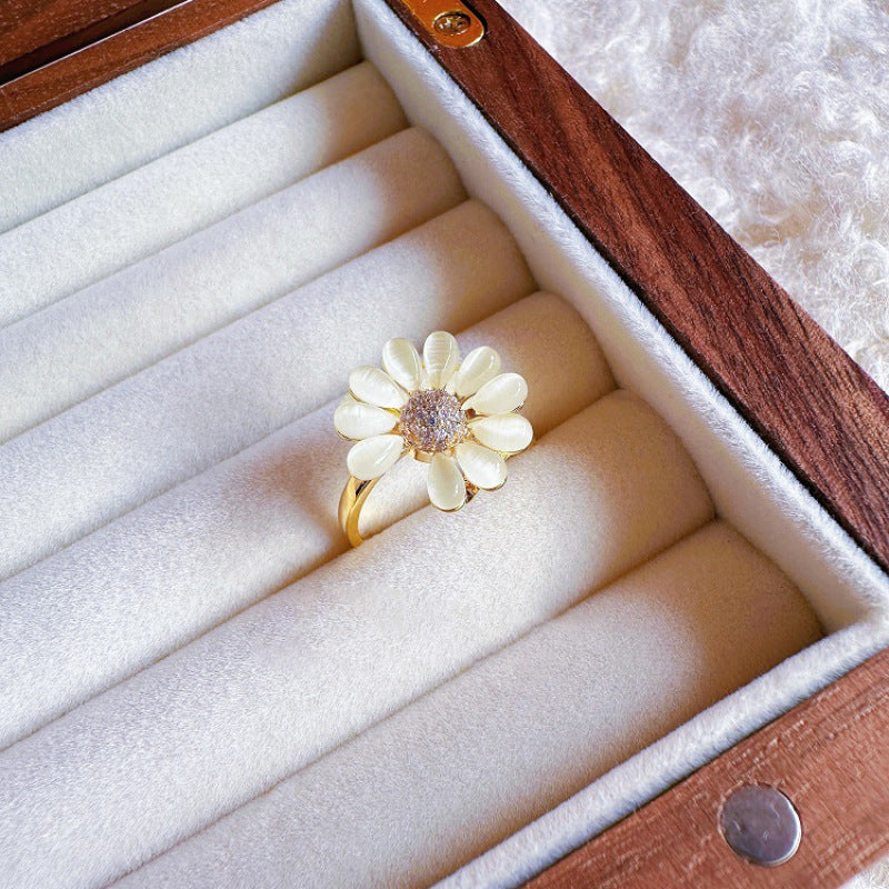Gold ring with a white flower design in a jewelry box