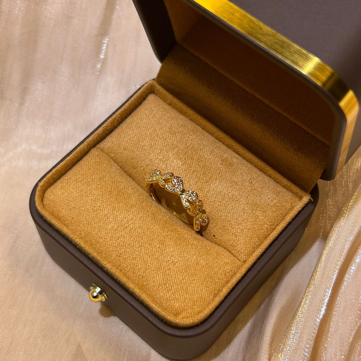Gold ring in a jewelry box on a beige fabric background
