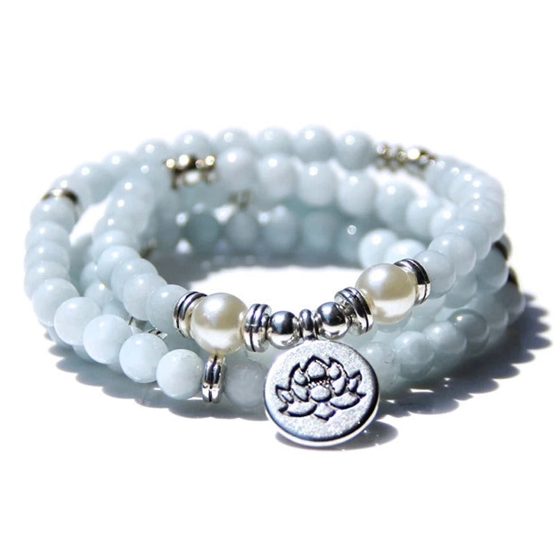 Stack of light blue beaded bracelets with pearl and silver lotus charm on a white background