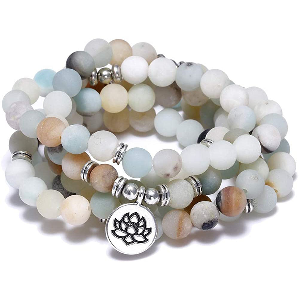 Stack of multicolored beaded bracelets with a central silver charm on a white background