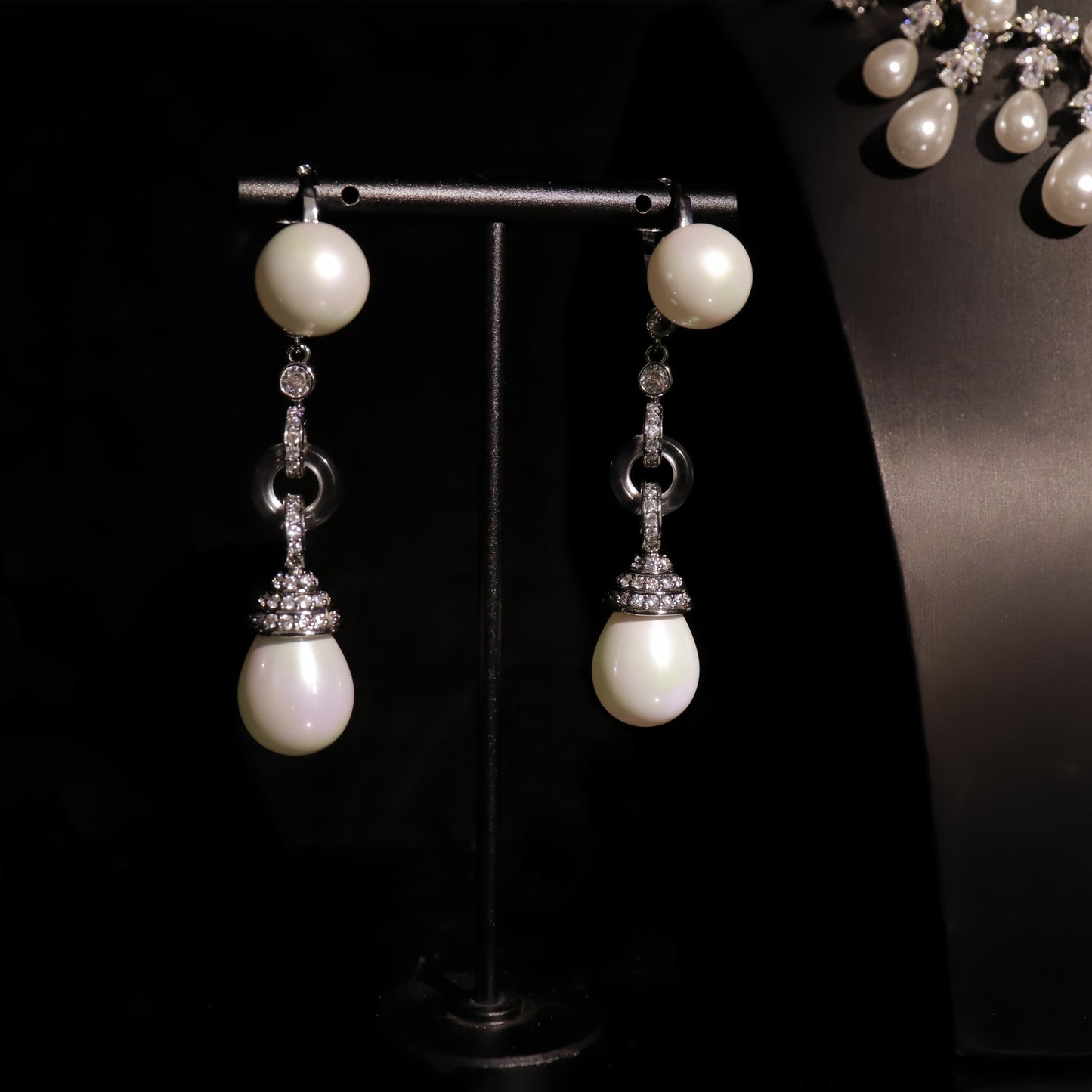 Pearl earrings with silver accents on a dark background