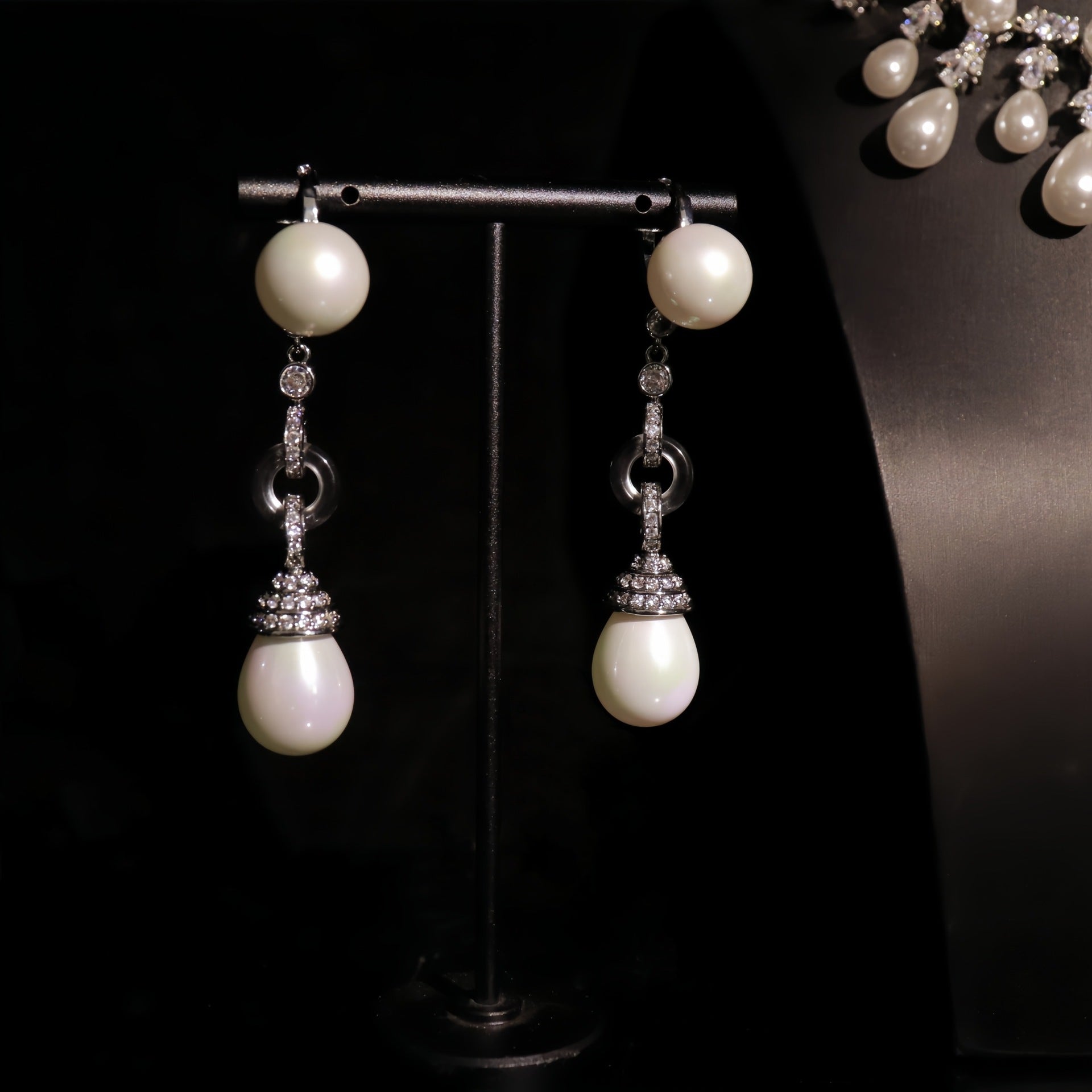 Pearl earrings with silver accents on a dark background