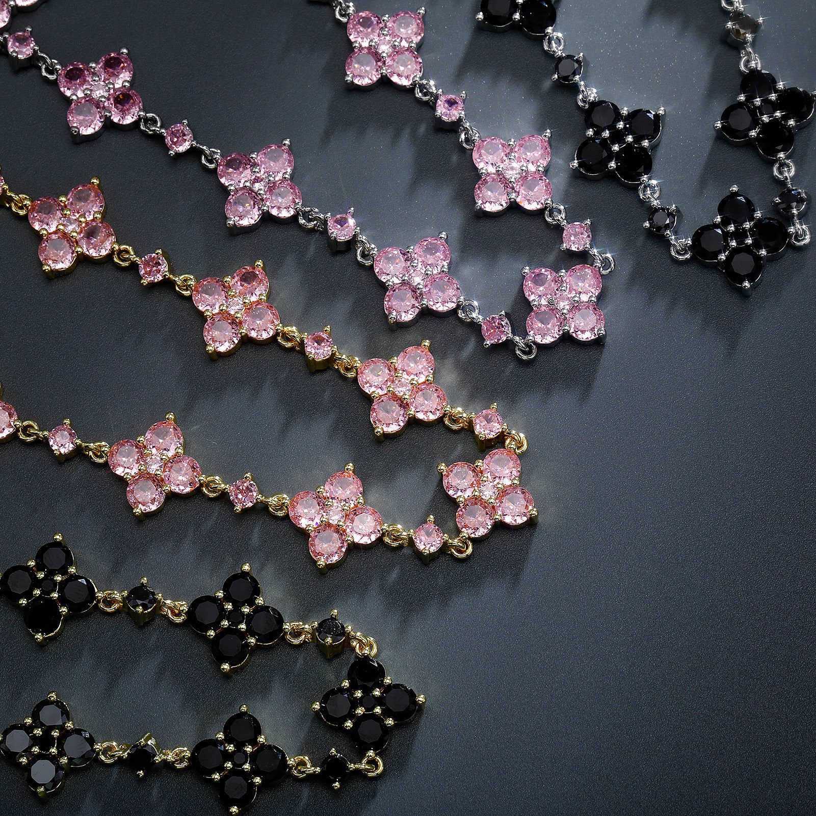 Necklaces with pink and black gemstones on a dark surface