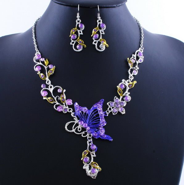 Jewelry set with necklace and earrings featuring purple butterfly and floral design on a black mannequin.