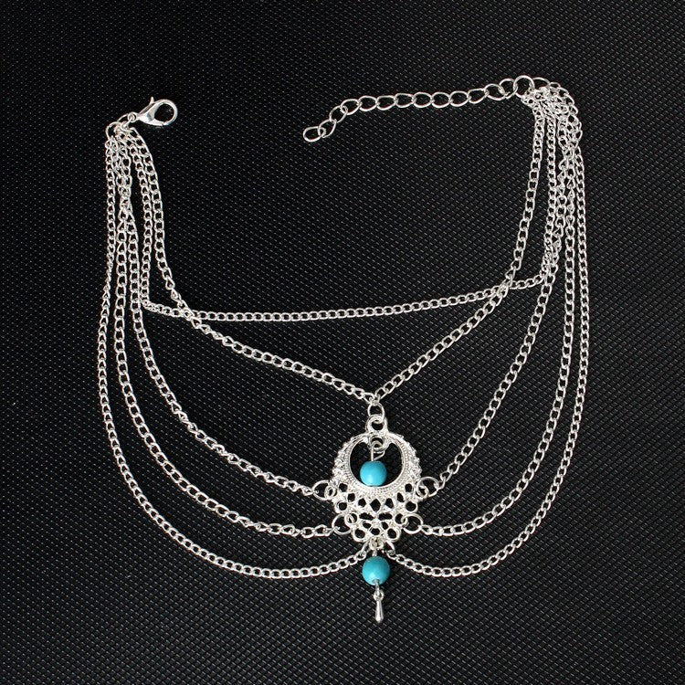 Multilayered silver necklace with turquoise beads on a black background