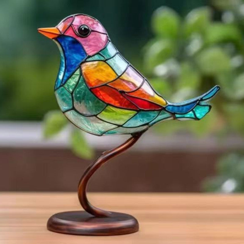 Colorful stained glass bird sculpture on a wooden surface with a blurred green background