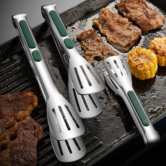 Set of four silver and green grilling utensils on a grill with meat and corn.