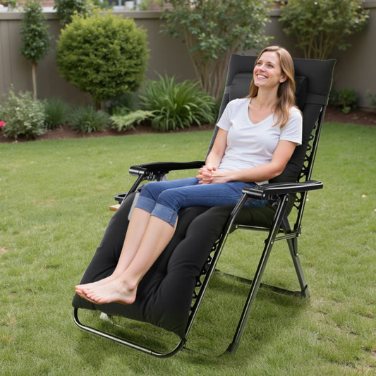 Woman sitting in a black reclining chair on a grassy area with plants in the background